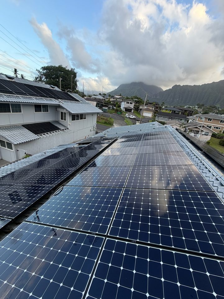 A long clean solar array running along a metal roofline, mountains in the distance