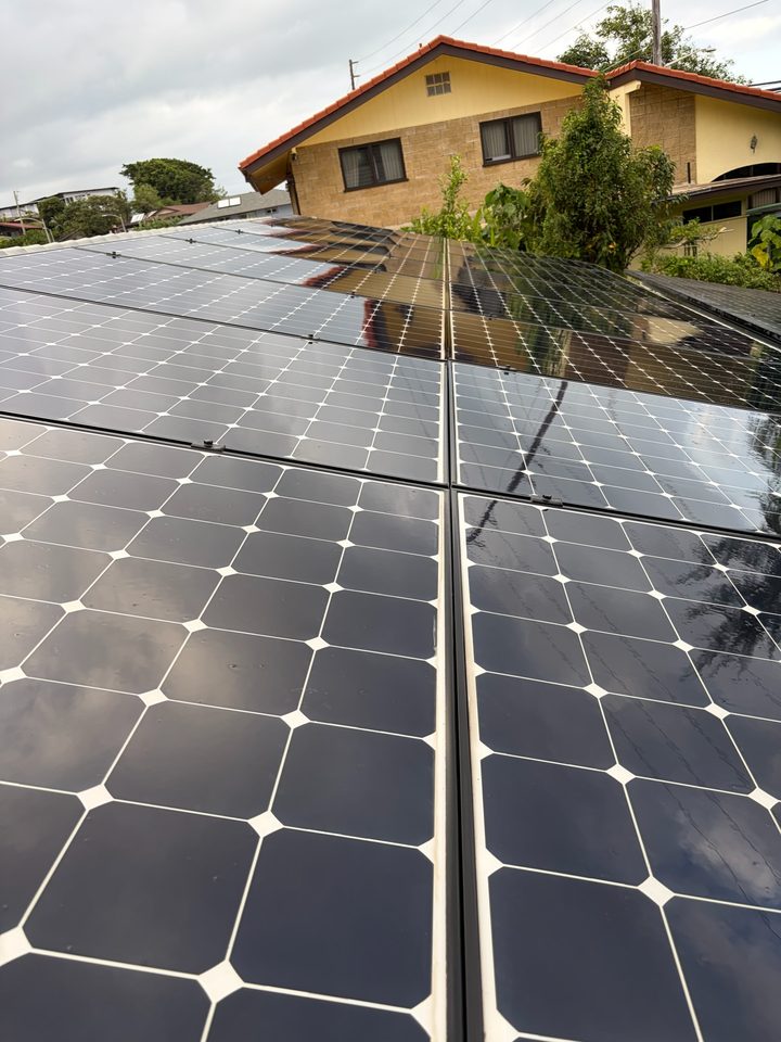 Clean solar panels on a metal tile roof looking toward a neighbor's home