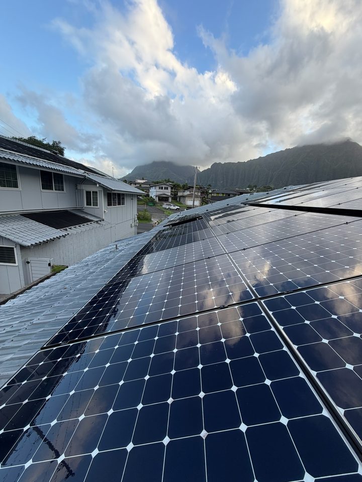 Clean solar panels on a metal roof with the mountain ridge and clouds behind