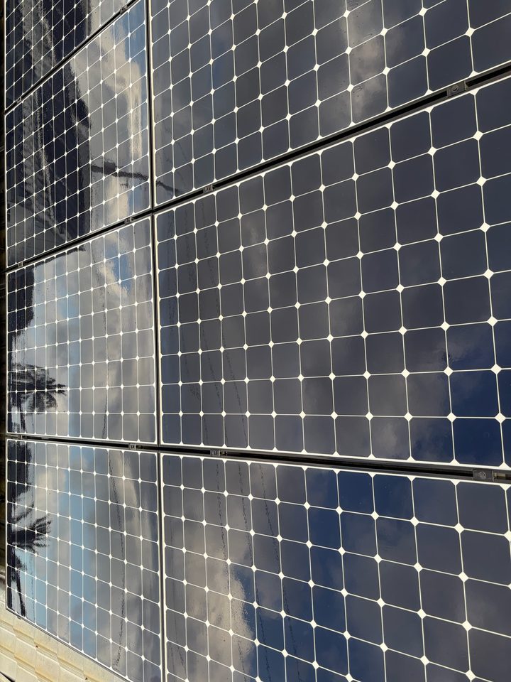 Clean solar panels reflecting clouds and blue sky
