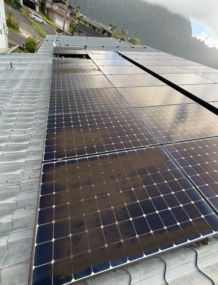 Dirty solar panels on a metal tile roof before cleaning, with brown film across the glass