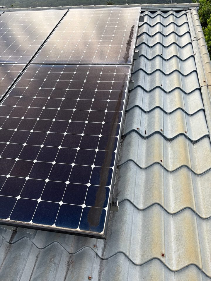 Grime built up along the bottom edge of a solar panel on a metal tile roof