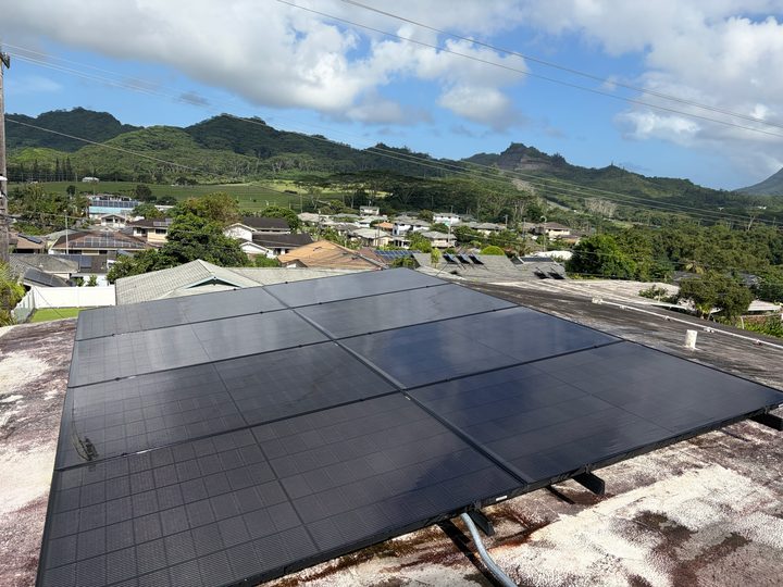 Black solar panels on a flat roof looking out over the valley and mountains