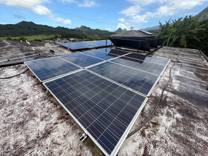 Solar panel array on a flat roof with the mountains and palms in the background
