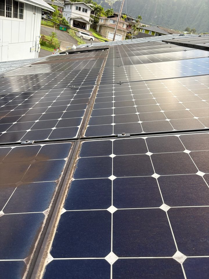 Solar panels halfway through a cleaning, the clean glass shining next to the dirty glass